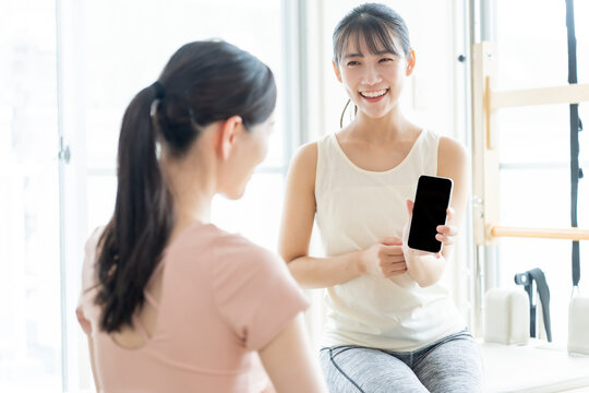 ピラティススタジオでスマートフォンを見せる女性