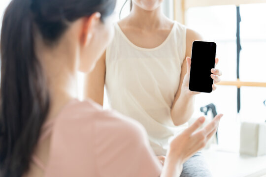 ピラティススタジオでスマートフォンを見せる女性