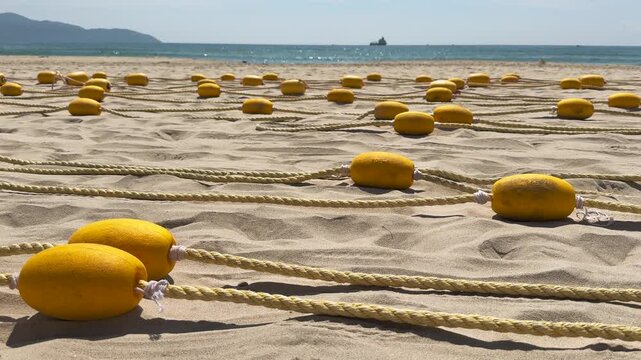 Close up of Yellow Beach Buoys Laid on Sand of the beach with Sea and Mountains in the Background