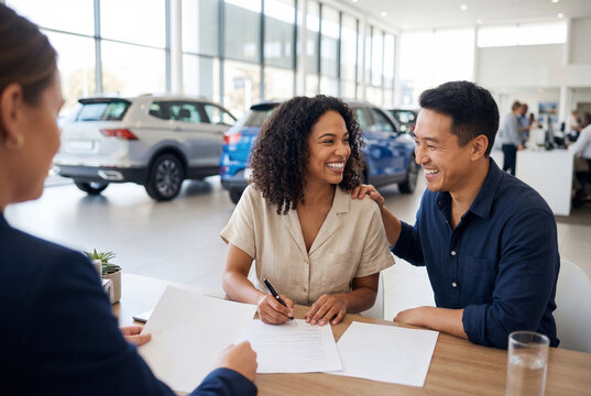 Happy couple signing contract papers at car dealership with salesperson