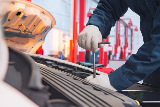 Auto mechanic repairing car engine with wrench at service station, real photography not AI generated.