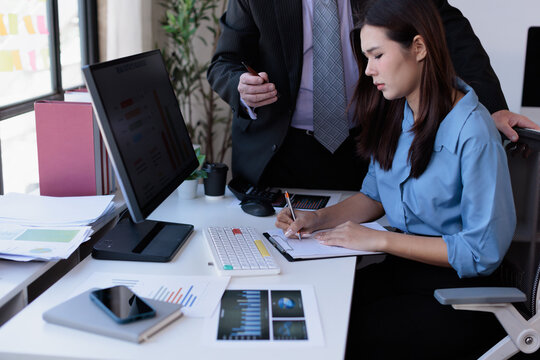 Male manager inappropriately touching female employee shoulder at office workplace, creating discomfort and an unprofessional environment
