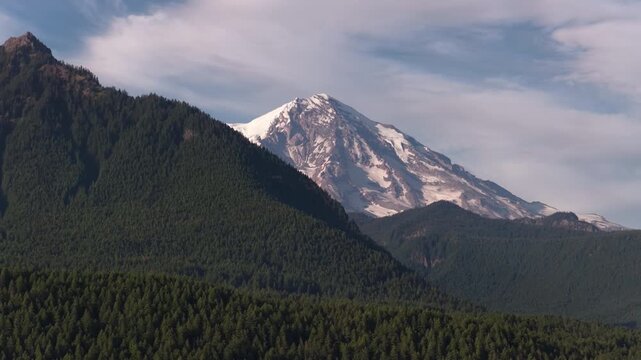 Aerial of snowcapped Mount Rainier in Gifford Pinchot National Forest Washington with evergreen slopes and snowfields