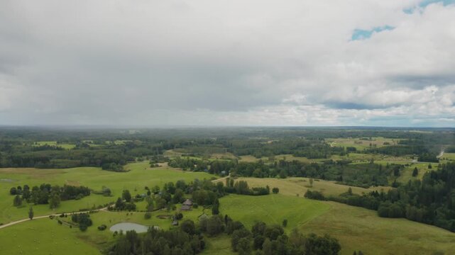 Wide aerial view of distant rain showers falling from heavy overcast storm clouds overcountryside forest landscape..