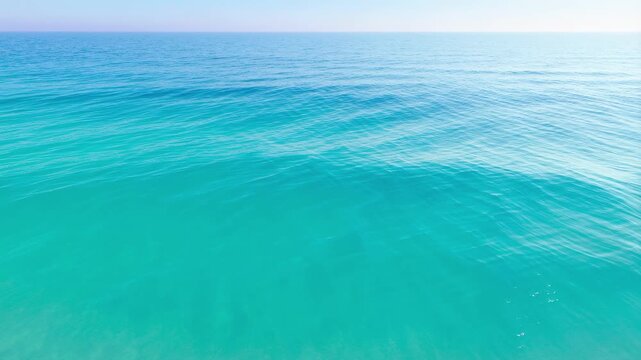 Aerial drone view of calm turquoise ocean waves rolling towards the sandy shoreline horizon