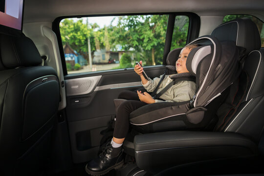preschool child girl watching rear entertainment screen or ceiling screen while sitting in car seat, safety baby chair travelling