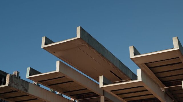 Low angle shot of brutalist concrete modular structures against clear blue sky in urban environment.