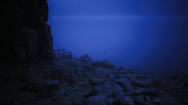 Calm shoreline under dim evening light and gentle waves. Serene seaside setting featuring wet stone formations and soft sounds of ocean during twilight hours