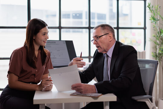 Hr manager discussing job application with young asian woman during a professional recruitment interview in a corporate office setting, hiring new talent