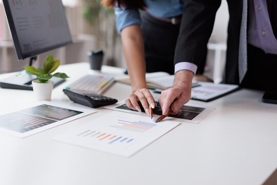 Business professionals analyzing financial data, discussing market trends, and collaborating on reports with charts outlining growth strategies in a modern office setup