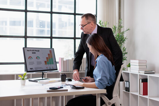 Business professionals analyzing financial data on a computer screen, collaborating on strategy, and discussing net profit margin 2030 projections in a modern office