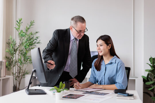 Experienced male manager guiding a smiling young asian businesswoman