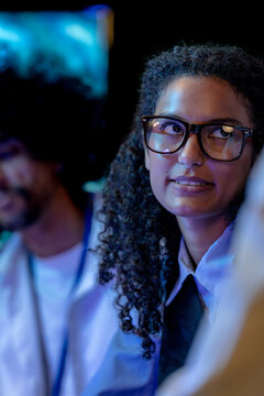 A curly-haired engineer and a curly-haired developer discuss a problem at the workstation in a modern technology office bathed in blue light, showcasing a diverse, multiethnic (frame 338)