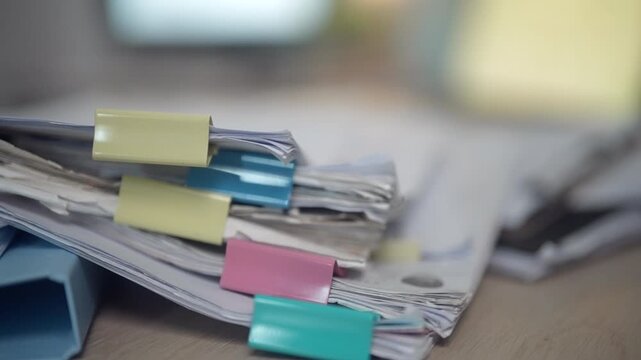 Stacked lawyer case files and legal documents organized with binder clips on an office desk. Ideal for legal practice, case management, law office administration, document review, paperwork, complianc