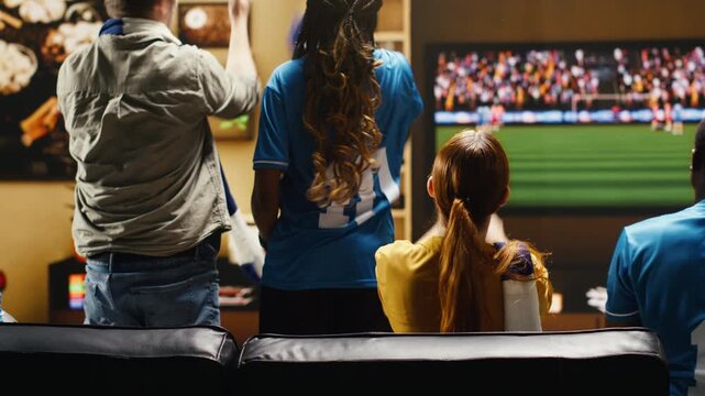 Upset football supporters at home watching match on television, cursing players after conceded goal with soccer fans showing annoyed body language during dramatic live game broadcast.
