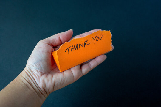 Hand Holding Orange Note with Thank You Message