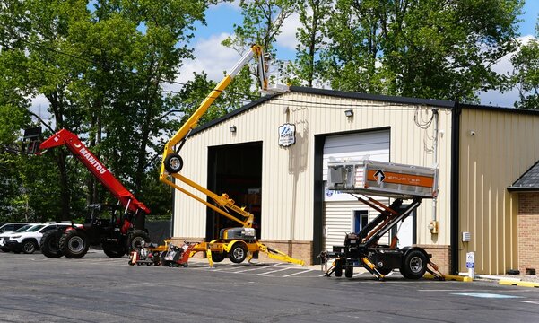 Clayton, Delaware, U.S.A - Jul 1, 2026 - Construction yard with Morse building and three machines - red Manitou handler, yellow Bil-Jax lift, and black Equipter trailer.
