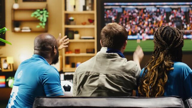 Football fans celebrate goal by toasting beer glasses during live match on TV as cheerful soccer supporters share a happy moment together, thrilled by favorite team victory and match excitement.