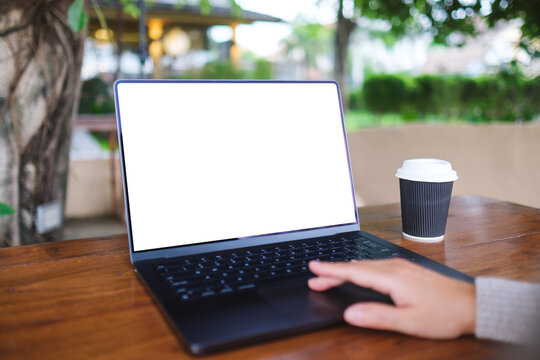 Mockup image of a woman working and touching on laptop computer touchpad with blank white desktop screen in cafe