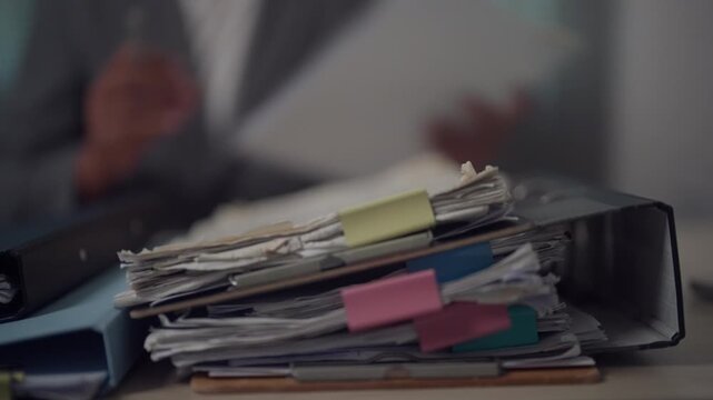 Stack of Office Paperwork and Business Documents Awaiting Review on Corporate Desk