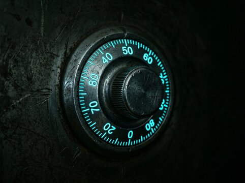 Close up of a vintage metal safe combination lock dial with glowing blue numbers