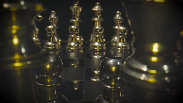 Golden and silver chess pieces arranged on a chess board with warm yellow and orange dramatic lighting in a luxurious setting.