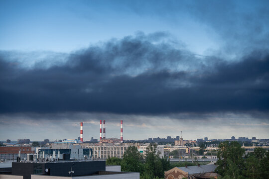Black toxic smoke from refinery plant covering industrial area in city, urban plant disaster and chemical industry, release of harmful heavy chemicals into atmosphere after major fire at facilities.
