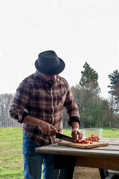 A man is cooking at a rustic outdoor table 