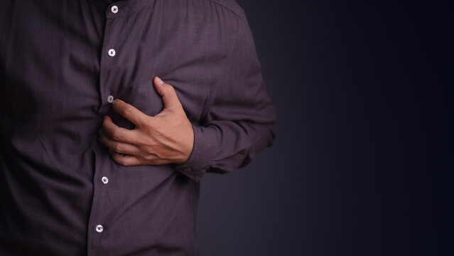 Adult man holding his chest experiencing a severe heart attack and chest pain. Medical, healthcare, and cardiovascular disease emergency concept.