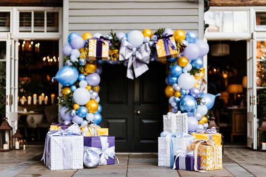 A festive building entrance decorated with balloon columns and gift boxes, featuring glossy textures and soft lavender tones for Christmas event inspiration