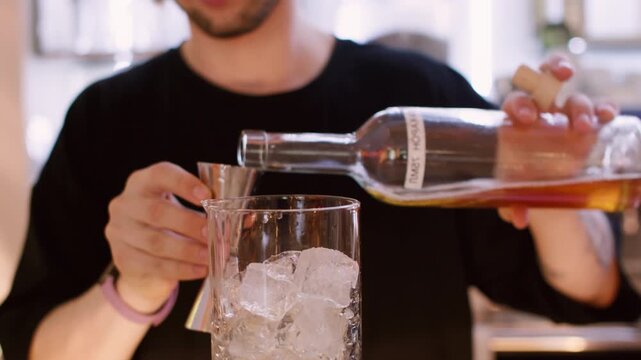 Preparing beverage mix. Making cocktail. Bartender pouring aroma color syrup from metal jigger to glass. Flavored refreshing drink.