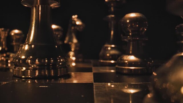Golden chess pieces on a dark reflective board with warm dramatic lighting creating a rich luxurious cinematic scene.