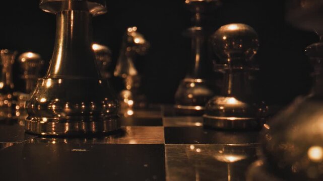 Golden chess pieces on a dark board with warm bokeh lighting and selective focus highlighting the king or queen piece.