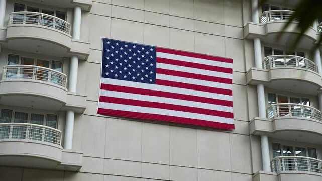 Detailed shot of a large American flag proudly displayed on the interior of Orlando International Airport's hotel tower, framed by balconies and tropical palms.