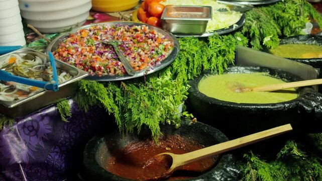Colorful traditional Mexican food buffet with fresh red and green sauces vegetables and condiments on display indoors