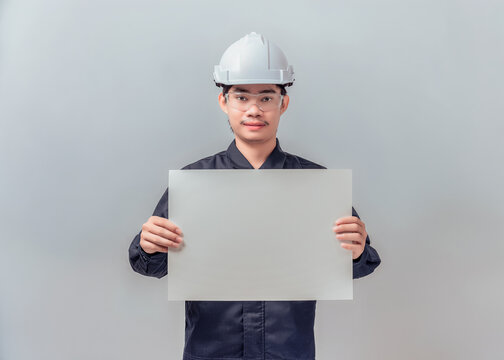 Asian male engineer holding large blank horizontal poster board. Concept for industrial construction announcement, project presentation mockup. High-quality studio shot.