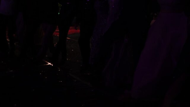 People dancing at an Indian wedding sangeet function, close up of legs and traditional outfits.