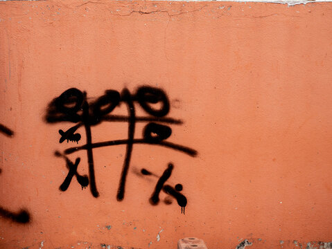 Black Spray Paint Graffiti Tag on Old Peach Orange Concrete Wall, Urban Street Art Texture