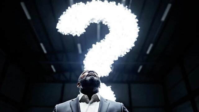A man in a suit looks up at a glowing question mark