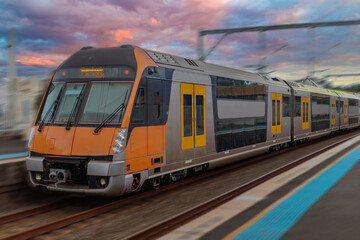 Fototapeta premium Passenger Train going through Lewisham Train Station at Sunset a suburban Sydney train Station in Sydney NSW Australia