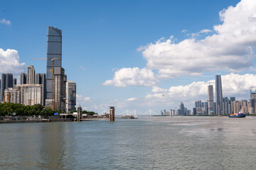 Fototapeta premium A view of the modern city skyline featuring tall buildings and skyscrapers along the river banks in Wuhan China under a bright blue sky with white clouds