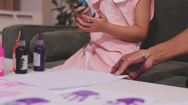 Small children hands hold wax crayons to draw rainbow on paper sheet. Diverse kids engage in creative craft activity together sitting on floor. Little students practice coloring skills at home school