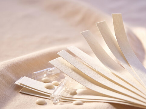Perfume tester paper strips with glass vials on beige fabric
