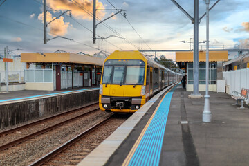 Fototapeta premium Passenger Train going through Lewisham Train Station at Sunset a suburban Sydney train Station in Sydney NSW Australia