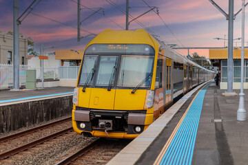 Fototapeta premium Passenger Train going through Lewisham Train Station at Sunset a suburban Sydney train Station in Sydney NSW Australia