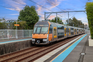 Fototapeta premium Passenger Train going through Lewisham Train Station at Sunset a suburban Sydney train Station in Sydney NSW Australia