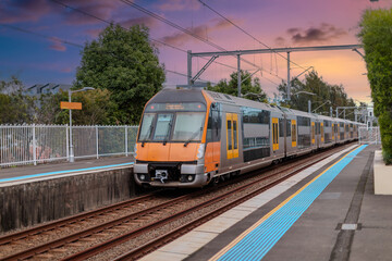 Fototapeta premium Passenger Train going through Lewisham Train Station at Sunset a suburban Sydney train Station in Sydney NSW Australia