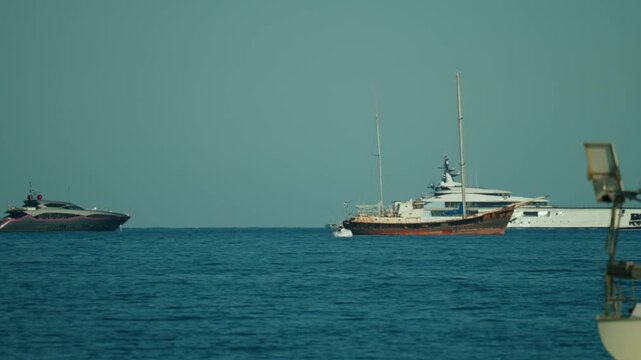 Different types of boats, including a modern luxury yacht and an older sailing ship, cruising the deep blue sea