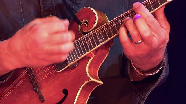 Close up view as man plays mandolin instrument during live concert