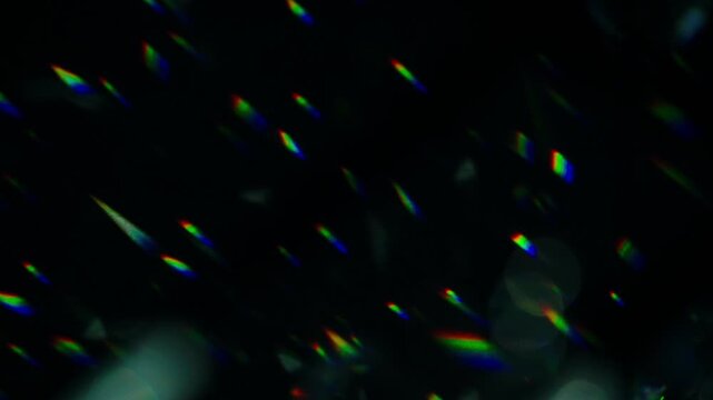 Colorful rainbow prism light leaks reflection flare streaks shining diagonally over dark abstract background static close up shot.